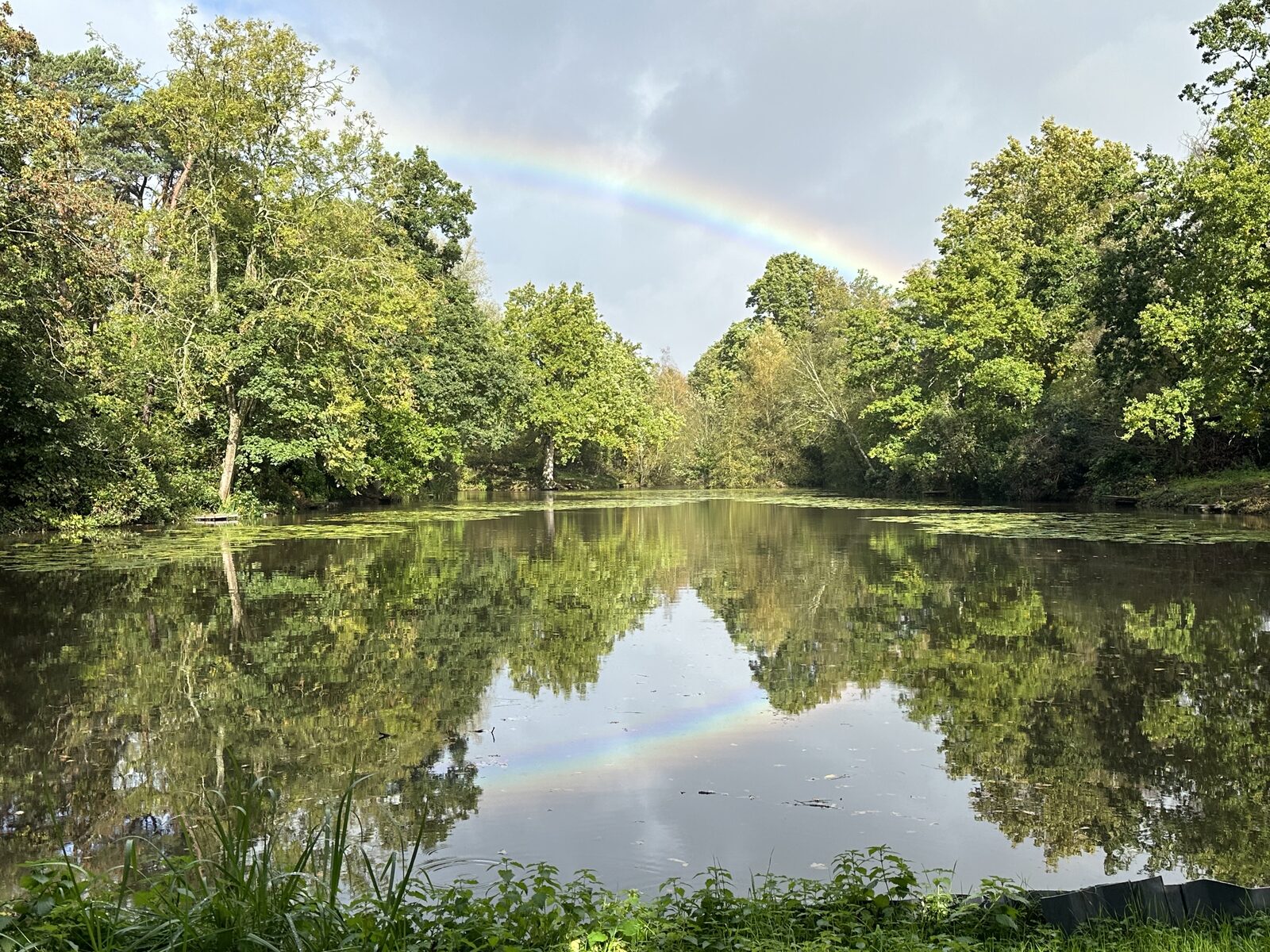 Rainbow over Bay Pond Shaw hammer pond after summer rain — the 1.3-acre medieval water body in the late afternoon light.